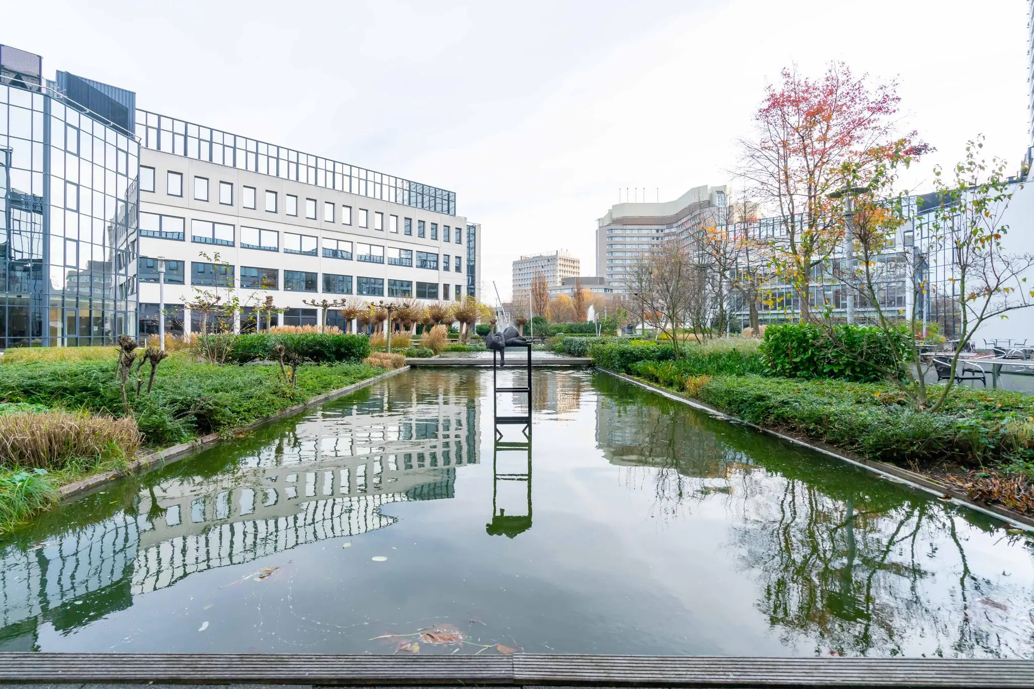 Moderne kantoorpanden aan de De Bruyn Kopsstraat met een vijver, beeldhouwwerk en groenvoorziening op de voorgrond.
